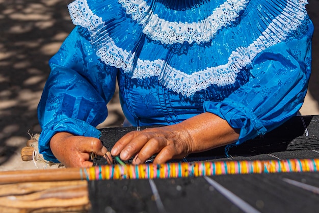 Manos de una mujer artesana trabajando en su telar