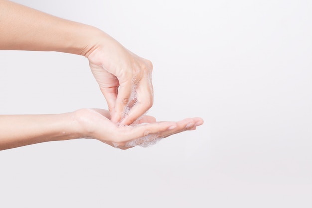 Las manos de la mujer asiática se lavan con pompas de jabón en blanco