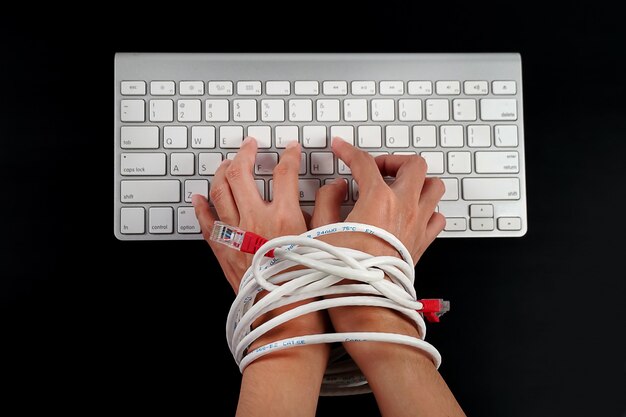 Manos de mujer atadas con cable de red