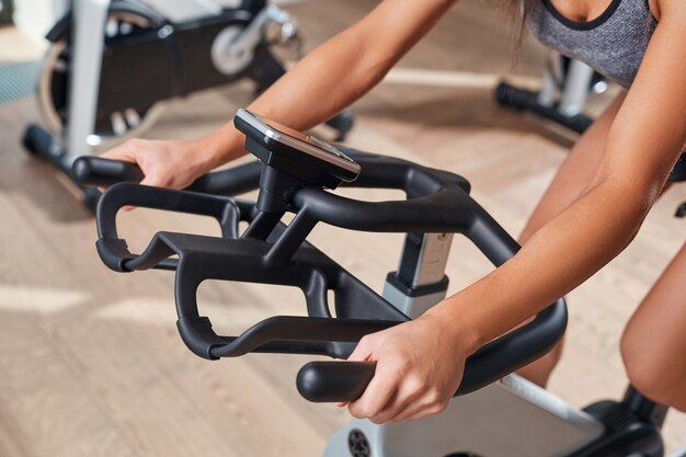 Manos de mujer en una barra de bicicleta estacionaria el gimnasio