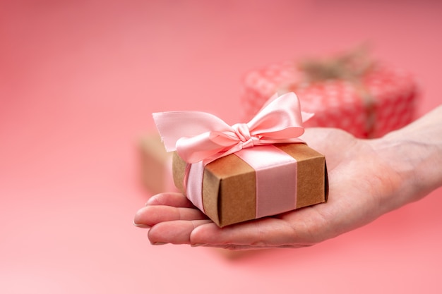 Manos de mujer con caja de regalo Embalado en papel kraft. Tarjeta navideña para el día de san valentín y de la mujer.