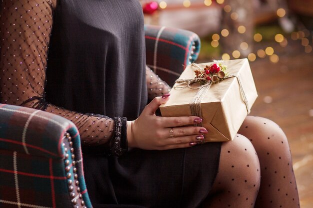 Manos de mujer con caja de regalo de oro. Escena festiva con bokeh.