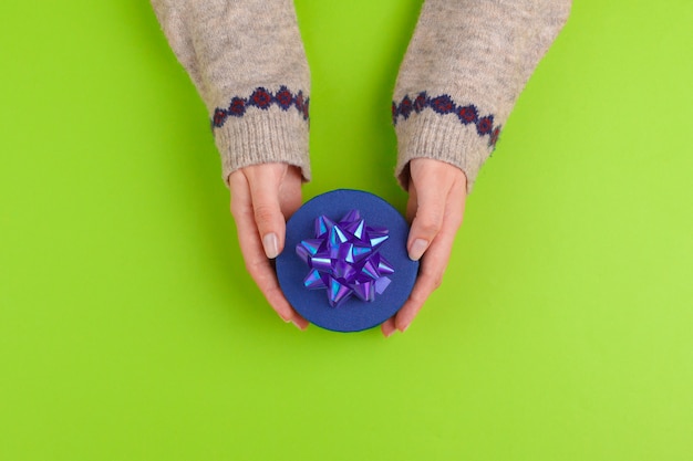 Manos de mujer con caja de regalo sobre fondo verde