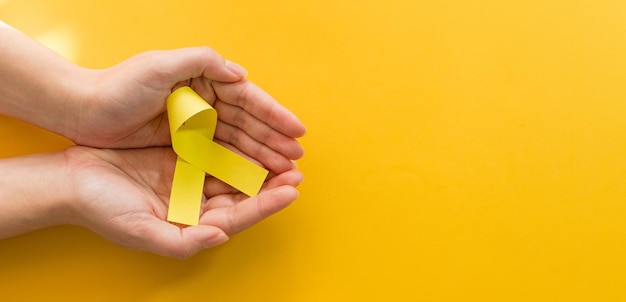 Manos de mujer con cintas de oro amarillo Conciencia del sarcoma