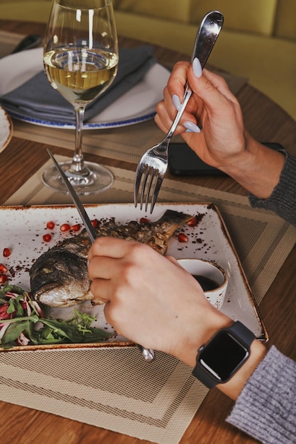 Manos de mujer comiendo un buen plato de alta cocina en la mesa del restaurante