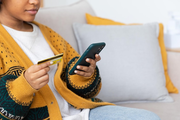 Manos de mujer compras en línea con teléfono inteligente pagando con tarjeta de crédito dorada chica afroamericana bu