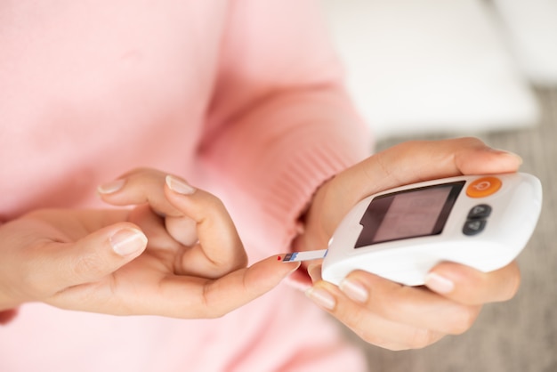 Foto manos de mujer comprobando el nivel de azúcar en sangre por medidor de glucosa para el probador de diabetes