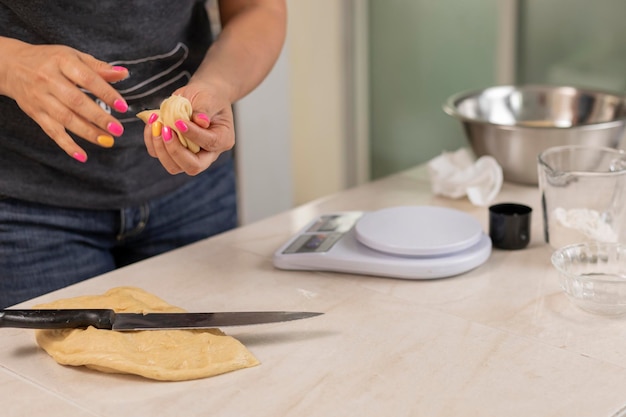 Manos de mujer cortando masa para hacer pan para pesar en una báscula