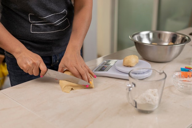 Manos de mujer cortando masa para hacer pan para pesar en una báscula