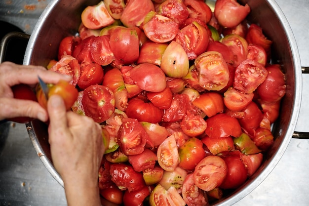 Manos de una mujer cortando tomates frescos por la mitad no se muestran rostros