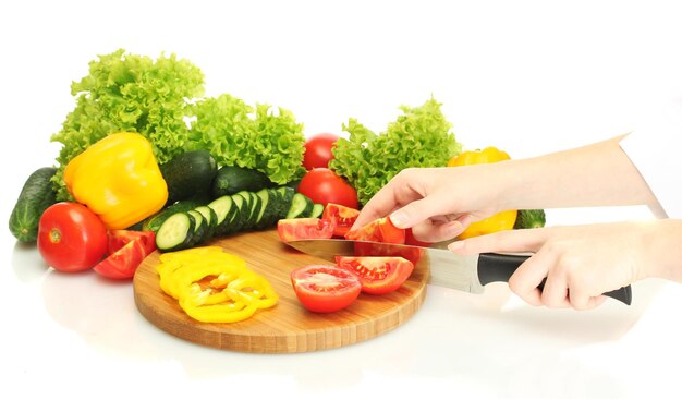 Manos de mujer cortando verduras en la pizarra de la cocina