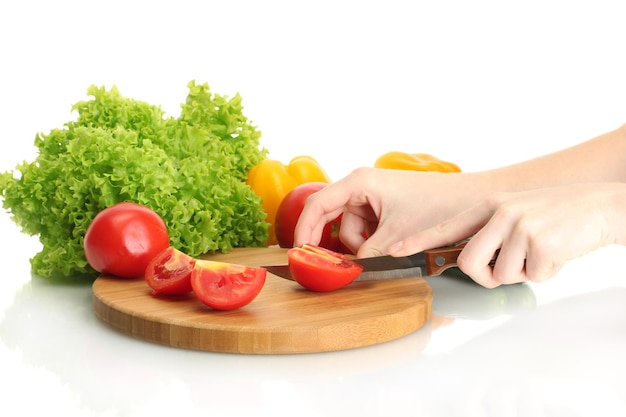Las manos de la mujer cortando verduras en la pizarra de la cocina