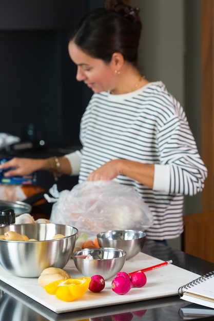 Manos de mujer cortando verduras en rodajas en una tabla de cortar