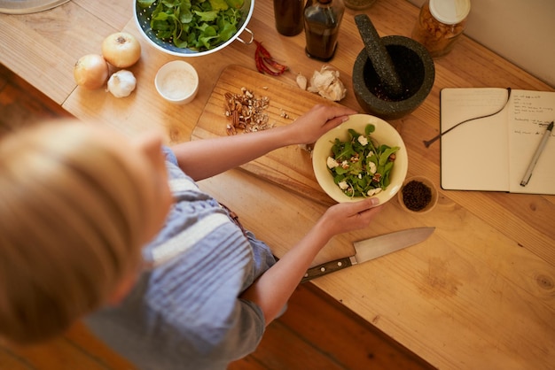 Las manos de la mujer y cortar ensalada con cuchillo bienestar y salud en un hogar de arriba tabla de madera vegana y cocinar con comida dietética en la cocina con ingredientes vegetales para la receta de almuerzo y nutrición