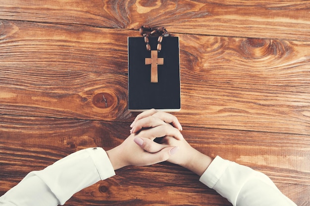 Foto manos de mujer cristiana rezando en un escritorio de madera