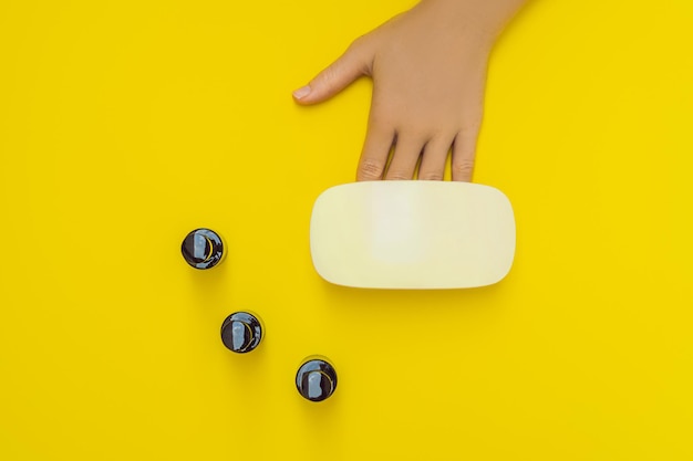 Las manos de la mujer cuidan las uñas cuidadas en los rayos de la lámpara uv curan el esmalte de gel arte de uñas pequeñas y manicura