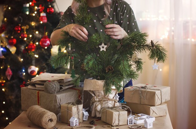 Manos de mujer decoran algunas ramas de coníferas con adornos hechos de materiales naturales