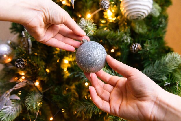 Manos de mujer decorando arbol de navidad arbol de navidad con adornos de wite y plata adornos de juguete ...