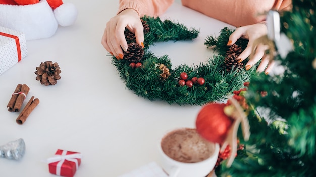 Manos de mujer decorar el árbol de Navidad y corona de Navidad.