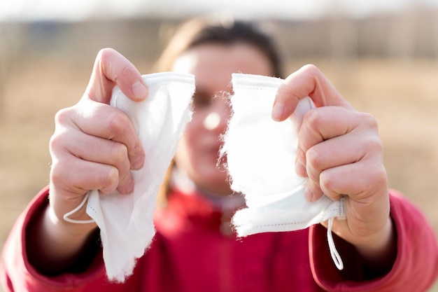 Manos de mujer desgarrando mascarilla médica desechable protectora Fin de cuarentena y autoaislamiento debido a la pandemia de covid19coronovirus Salida de casa a la calle Camine al aire libre en la naturaleza