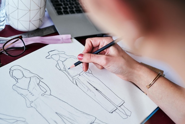 Manos de mujer y diseñadora de moda dibujando en papel para planificar una idea o dibujar en el escritorio de la oficina