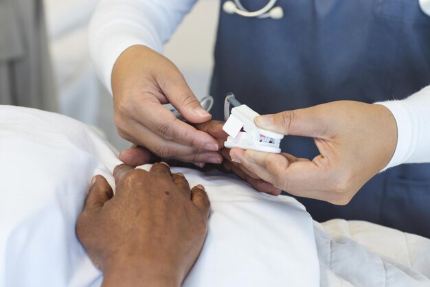 Las manos de una mujer doctora diversa y una paciente anciana en una habitación del hospital