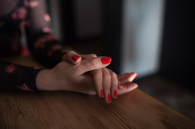 Manos de mujer con elegante manicura roja sobre fondo negro de cerca