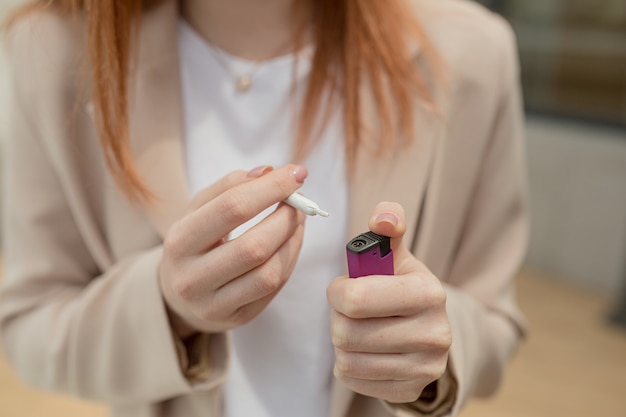 Manos de mujer encienden un cigarrillo