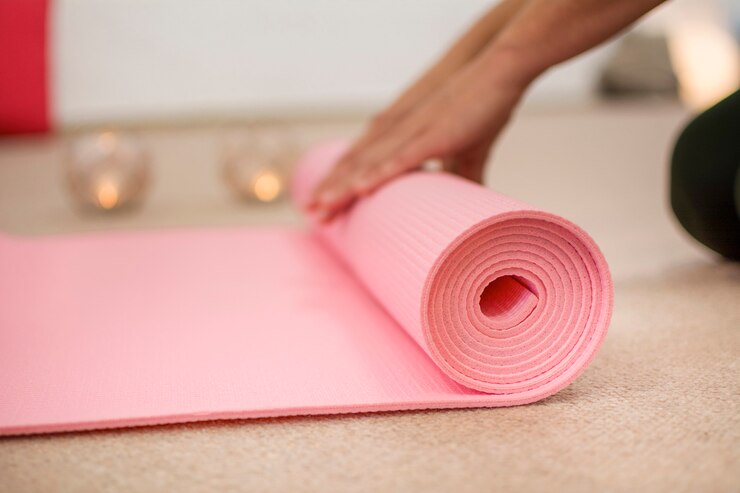 Manos de mujer enrollando la estera de yoga rosa.