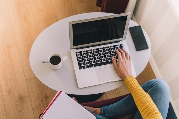 Manos de mujer escribiendo en su computadora portátil en casa. Concepto de trabajo a domicilio y productividad.