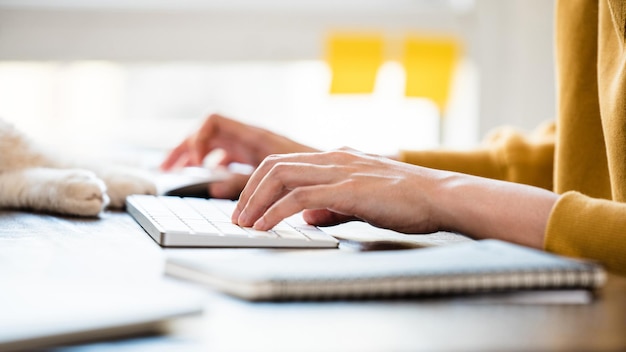 Manos de mujer escribiendo en el teclado de la computadora en la mesa en casa