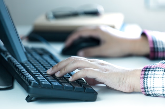 Las manos de la mujer escribiendo en el teclado de escritorio.