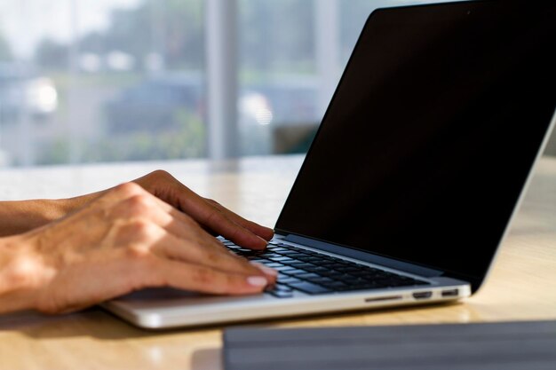 Manos de mujer escribiendo en el teclado del portátil en el concepto de negocio y tecnología de la oficina soleada Cerrar