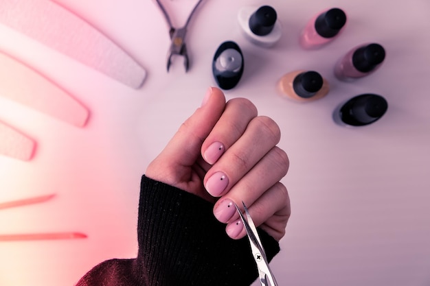 Las manos de la mujer, el esmalte de uñas, las herramientas de manicura, la mesa, la vista plana, cómo hacer manicura en casa, el concepto.