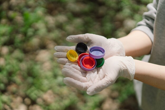 Las manos de la mujer están sosteniendo un puñado de coloridas tapas de plástico concepto de contaminación ambiental comportamiento ecológico