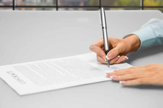 Foto manos de mujer firmando papeles de oficina. primer plano del papeleo diurno de la secretaria. una firma hace muchos cambios. piense antes de firmar.