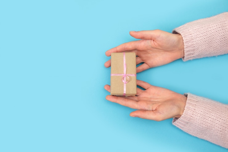 Foto las manos de la mujer guardan la caja con el regalo en azul.