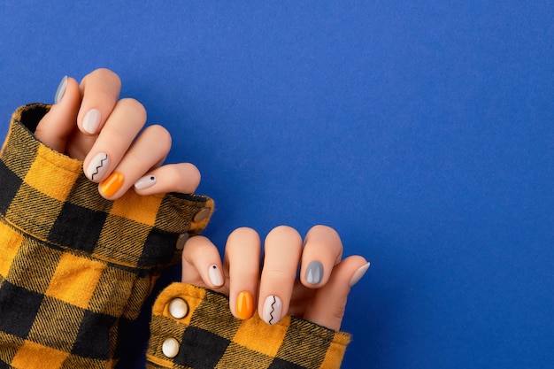 Manos de mujer hermosa con diseño de uñas mínimo sobre fondo azul Concepto de salón de belleza de pedicura de manicura