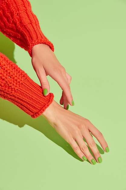 Manos de mujer hermosa con diseño de uñas de primavera otoño sobre fondo verde Concepto de salón de belleza de pedicura de manicura Lugar vacío para texto