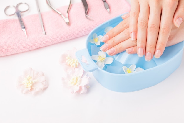 Manos de mujer hermosa con manicura en un tazón de agua