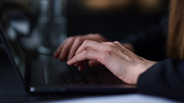 Manos de mujer irreconocibles escribiendo en una computadora portátil en un lugar de trabajo remoto