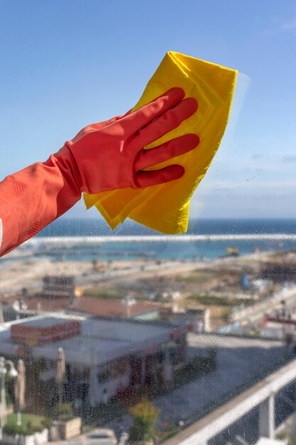 Manos de mujer irreconocibles con guantes protectores limpiando la casa