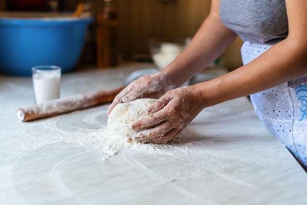 Manos de una mujer joven amasando masa para hacer pan o pizza en casa Producción de productos de harina Elaboración de masa por manos femeninas