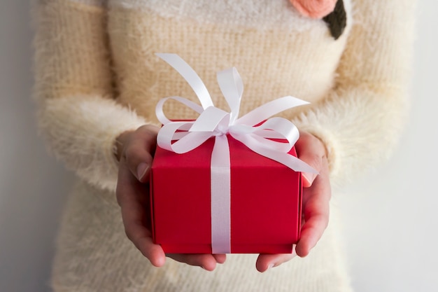 Manos de mujer joven con caja de regalo roja