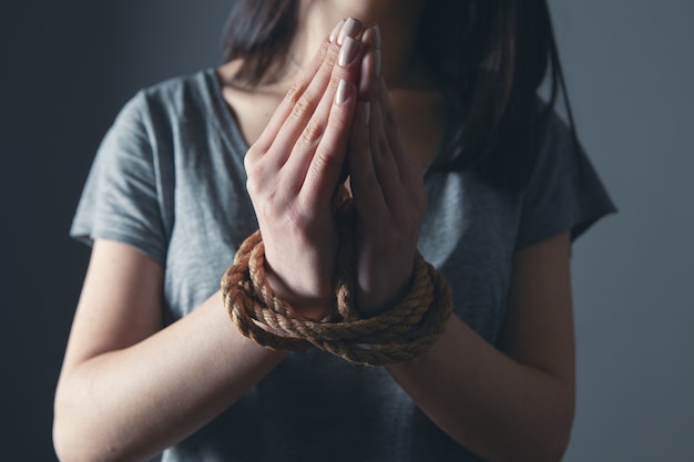 Las manos de una mujer joven están atadas con una cuerda.