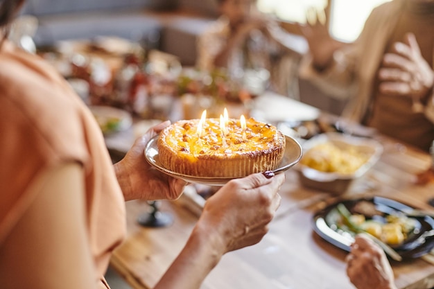 Manos de mujer joven sosteniendo la placa con tarta de cumpleaños casera