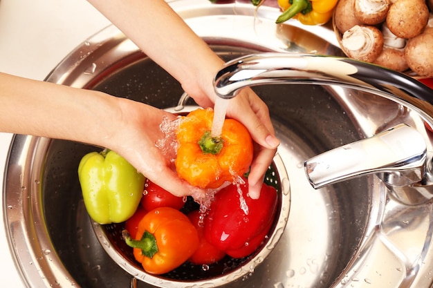 Foto manos de mujer lavando verduras en el fregadero de la cocina