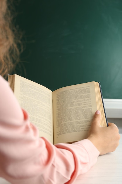 Manos de mujer con libro sobre fondo de pizarra