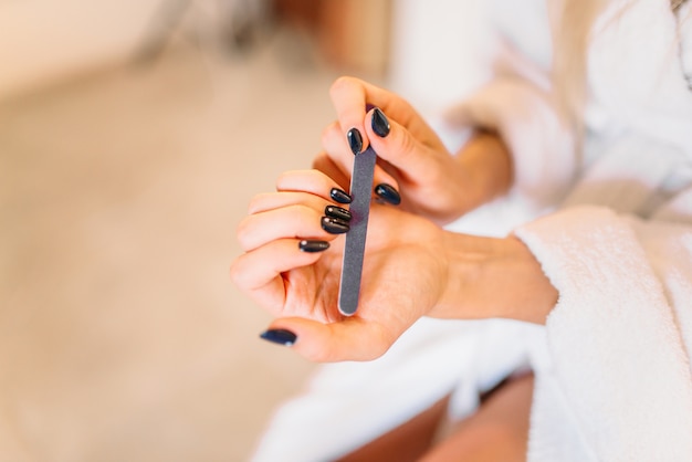 Manos de mujer con lima de uñas, manicura