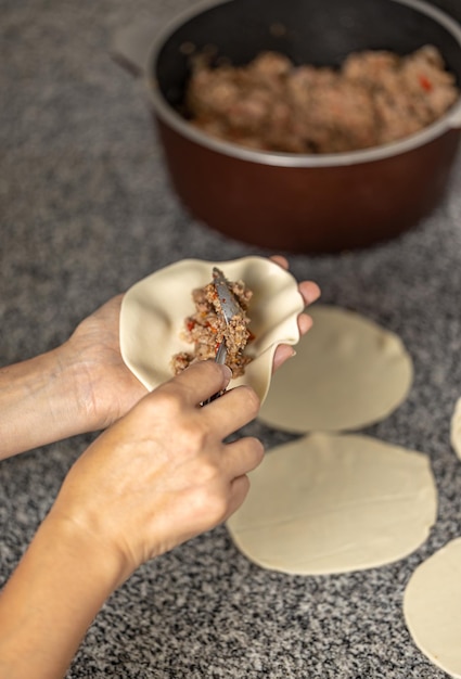 Manos de mujer llenando una empanada de carne argentina